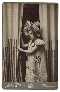 Ein Mädchen mit Hut vor einem Vorhang